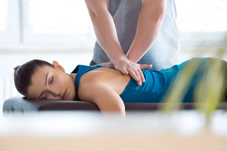 A person receiving a chiropractic or physical therapy adjustment to their back from a medical professional. The image illustrates the relief provided by expert Pain Management Port St Lucie Clinics.