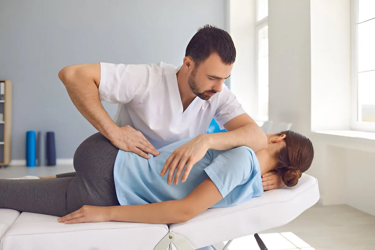 A licensed chiropractor in Port St. Lucie performs a precise back adjustment on a female patient lying on a chiropractic table. The image represents professional and effective Port St. Lucie Chiropractic Adjustments.