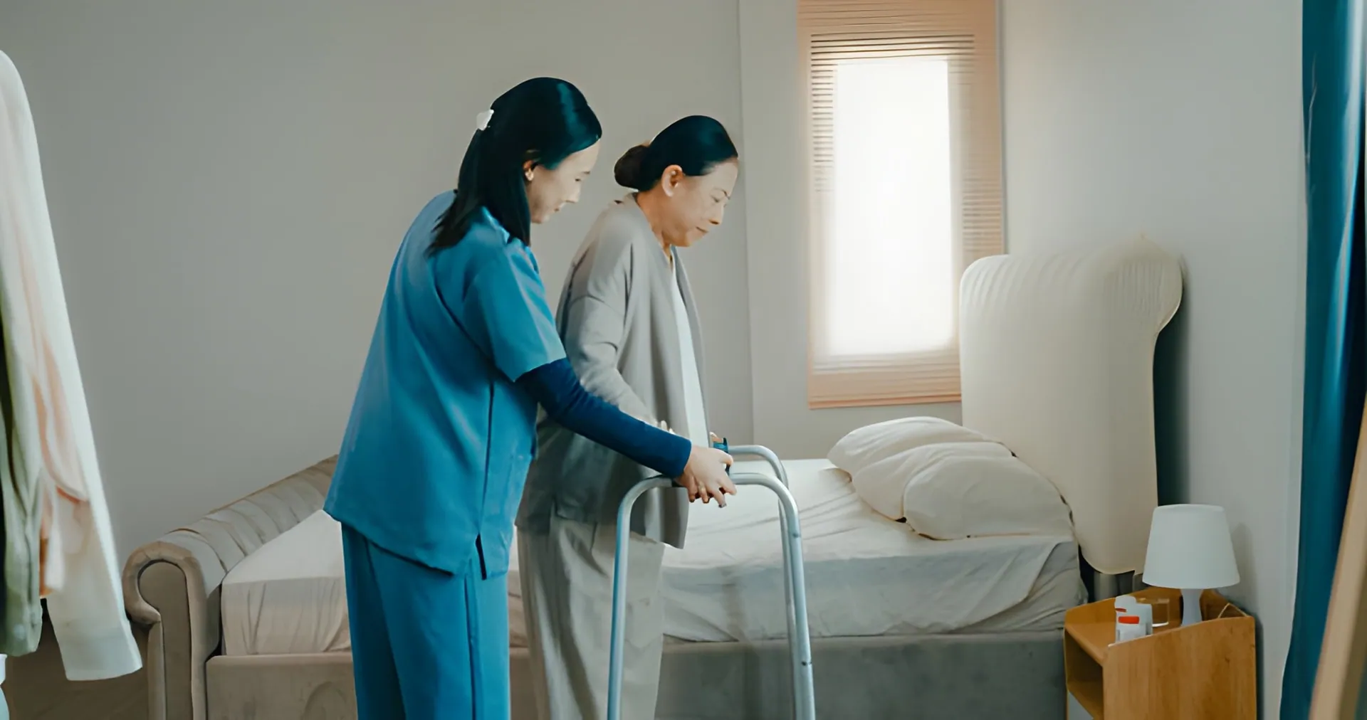 A healthcare professional, possibly a nurse or caregiver, gently assisting an elderly woman who is using a walker in a brightly lit bedroom. This illustrates dedicated Physical Therapy Port St Lucie for rehabilitation.