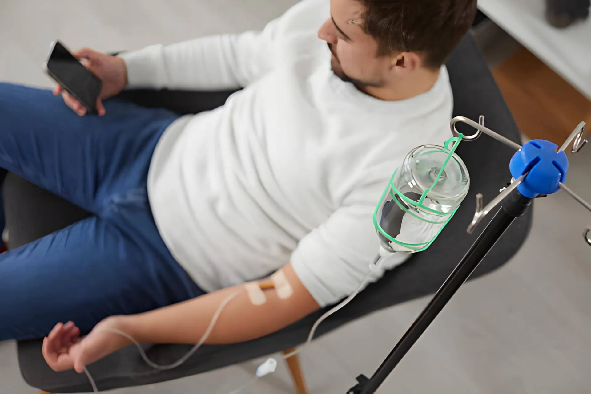 IV therapy near me—person seated with IV line connected to fluid bag in clinical setting.