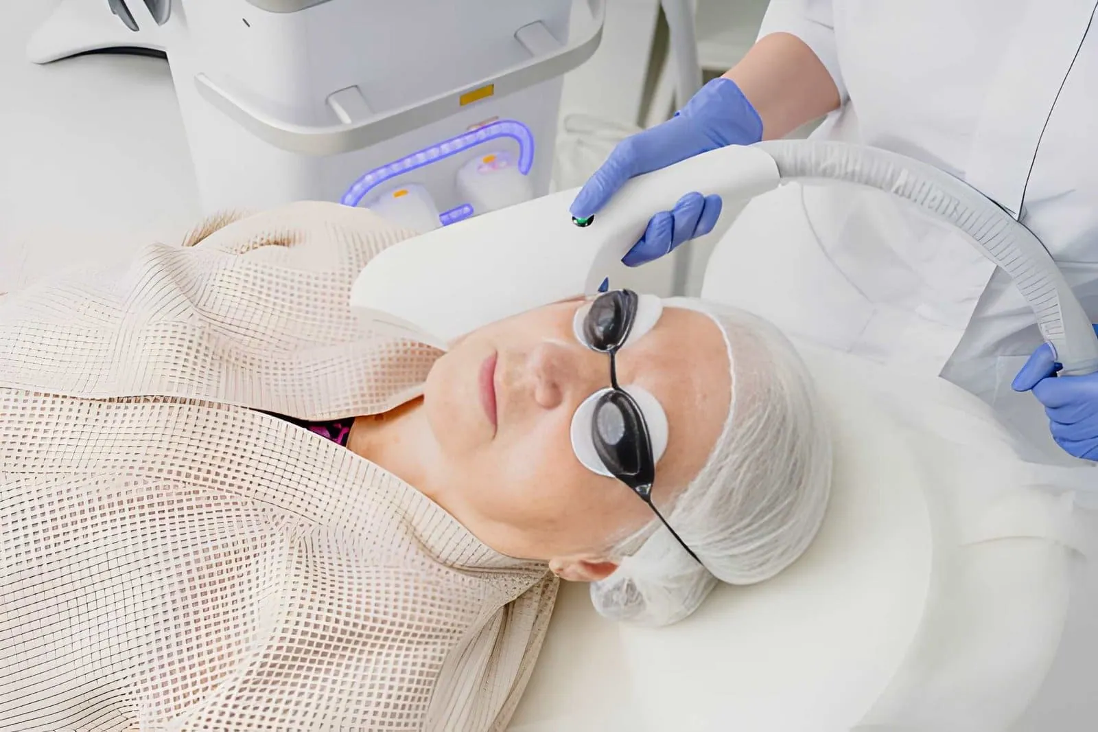 Laser aesthetics near me—professional using handheld device for facial treatment with protective eyewear.