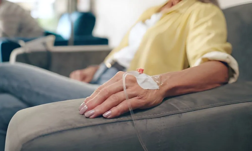 IV therapy near me—close-up of patient’s hand with IV catheter and tubing in clinical setting.